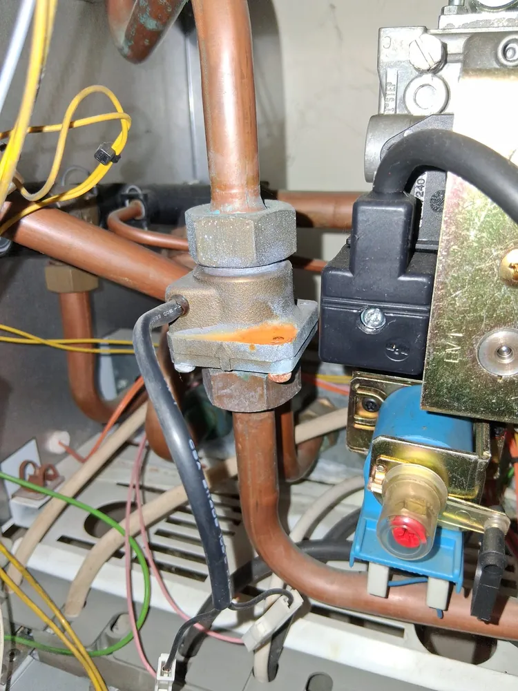 Inside a gas boiler during a service, showing the gas valve and pipework
