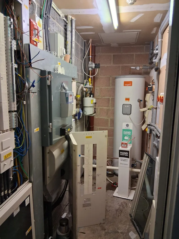 Plant room with gas meter, pipework and an unvented hot water cylinder